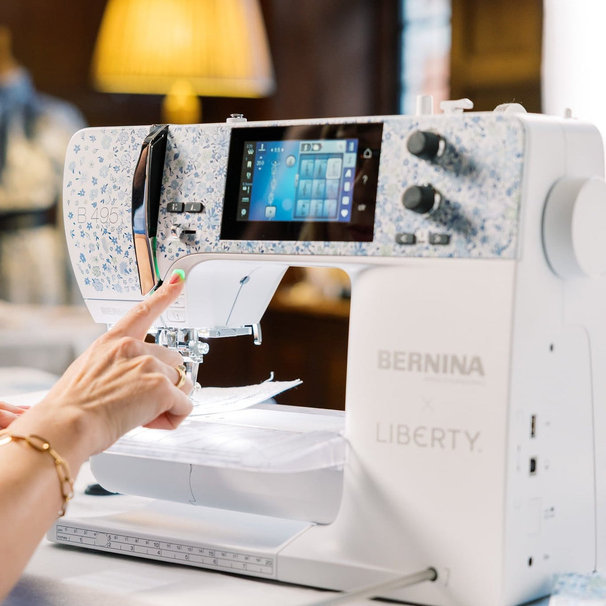 Person using a Bernina Liberty sewing machine with a blurred indoor background