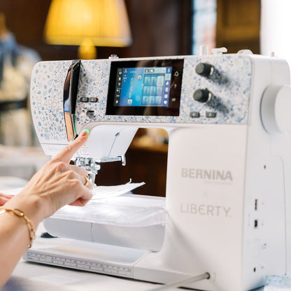 Person using a Bernina Liberty sewing machine with a blurred indoor background