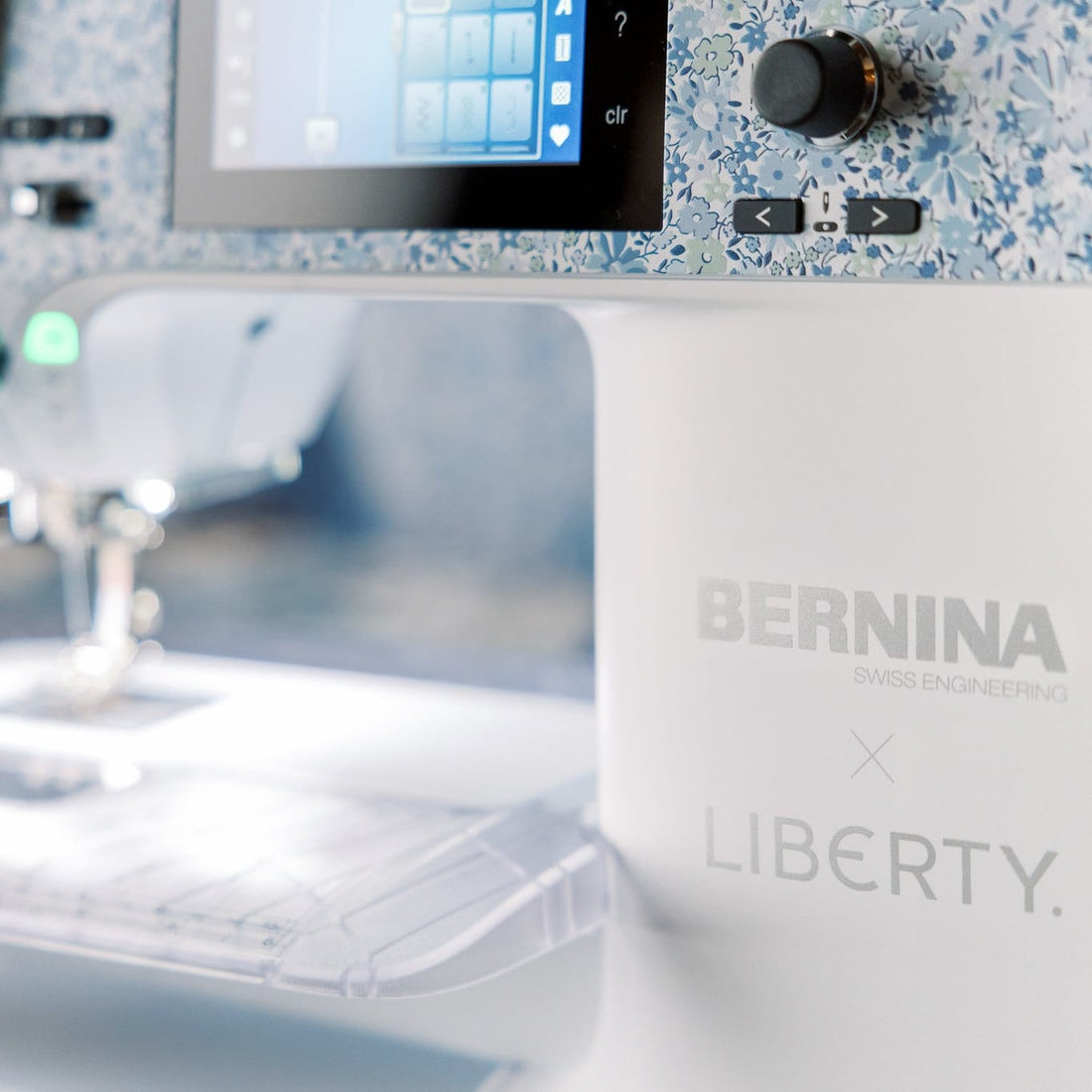 Close-up of a BERNINA sewing machine with a white body, blue-and-white speckled trim, a digital display screen, and the BERNINA x LIBERTY branding on the front.