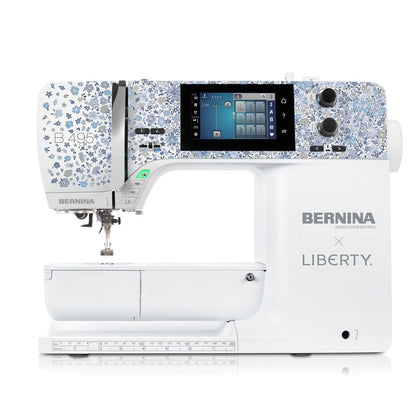 A white Bernina sewing machine with a blue and white floral patterned head, featuring a digital screen and the text 'BERNINA x LIBERTY' on the side, shown against a solid white background.