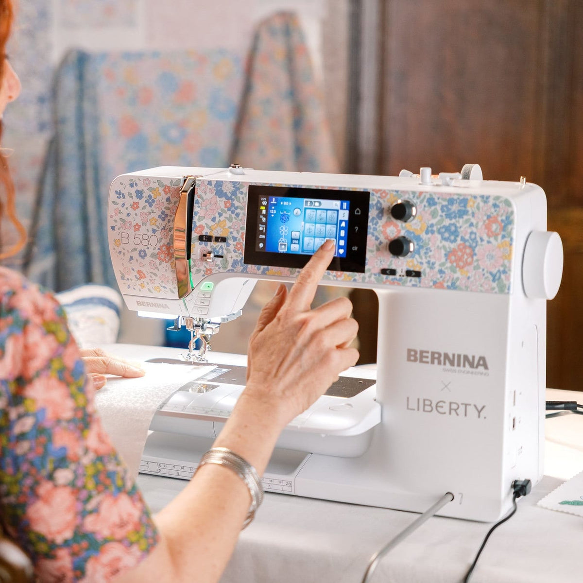 Person using a Bernina Liberty sewing machine with a colorful fabric design on the screen.