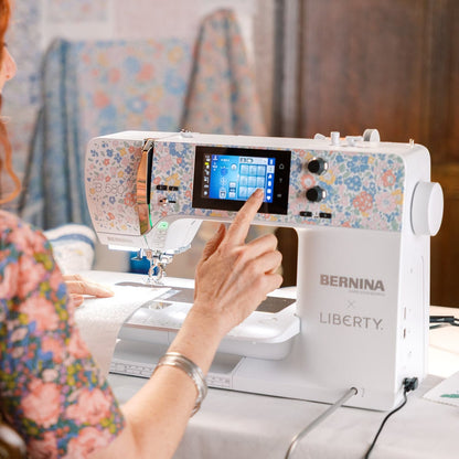 Person using a Bernina Liberty sewing machine with a colorful fabric design on the screen.