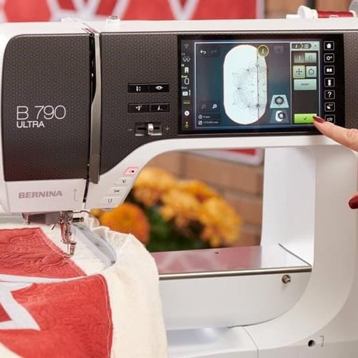 A close-up of a BERNINA B.790 Ultra sewing machine with a person's hand touching the touchscreen interface.