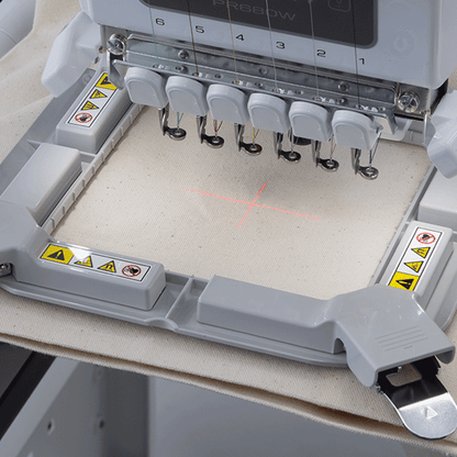 Embroidery machine with needle bar on a beige fabric background