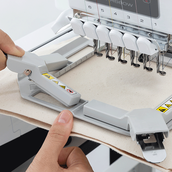 Embroidery machine with a person adjusting a piece of fabric.