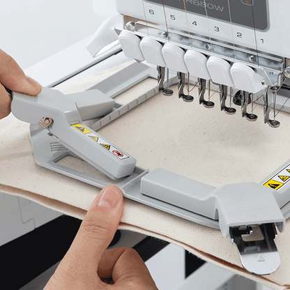 Embroidery machine with a person adjusting a piece of fabric.