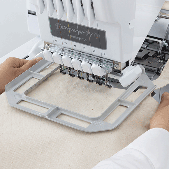 Embroidery machine in use with a person operating it on a white background