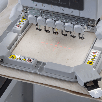 Embroidery machine with needle bar on a beige fabric background