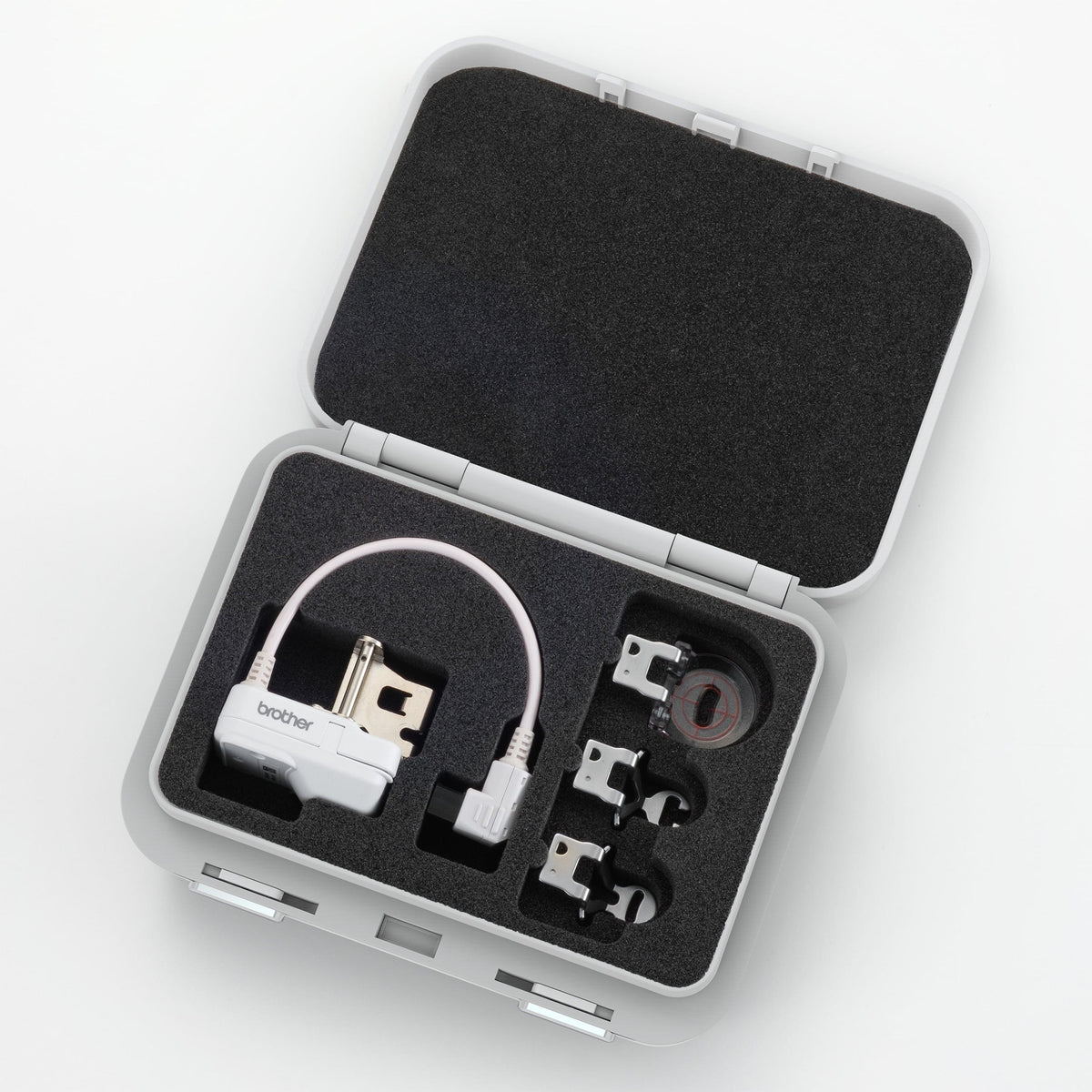 An open gray hard carrying case with black foam insert, containing a white electronic device with a cable and several small accessories, photographed on a clean white background.