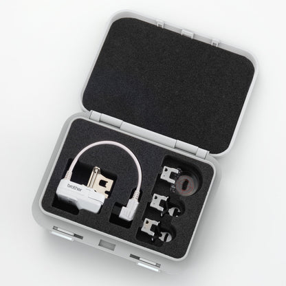 An open gray hard carrying case with black foam insert, containing a white electronic device with a cable and several small accessories, photographed on a clean white background.