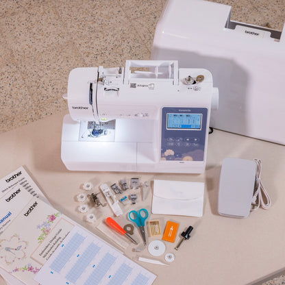 A Brother sewing machine set displayed on a tabletop, including the white sewing machine, a large white storage box, an electric motor, thread spools, needles, scissors, and printed manuals.
